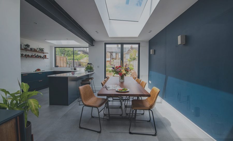 Kitchen and dining area with a blue feature wall, rooflight and tan leather chairs