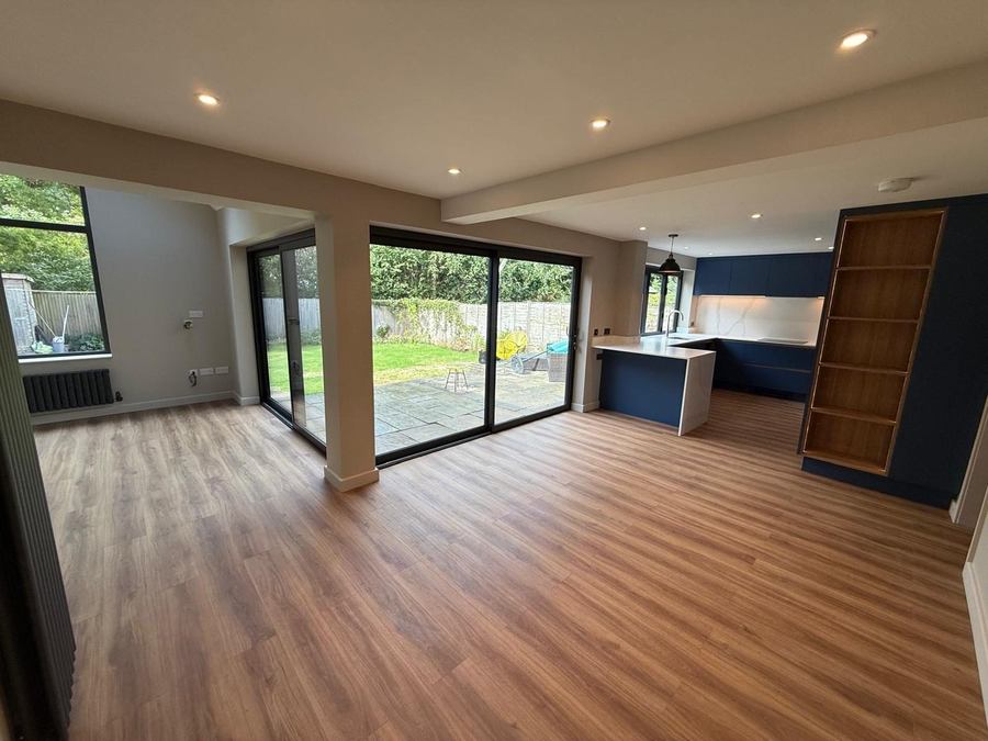Open-plan kitchen extension with wood flooring, a navy kitchen and sliding doors to the garden