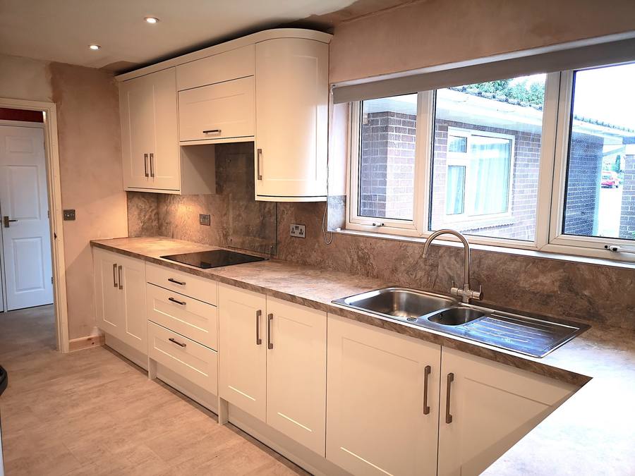 Cream shaker kitchen with a tiled splashback and a window over the sink