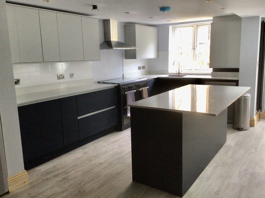 Kitchen with a dark island, pale wall units and a window seat